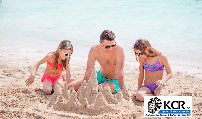 Father and two daughters build sand castle on beach during summer vacation; air conditioning maintenance.