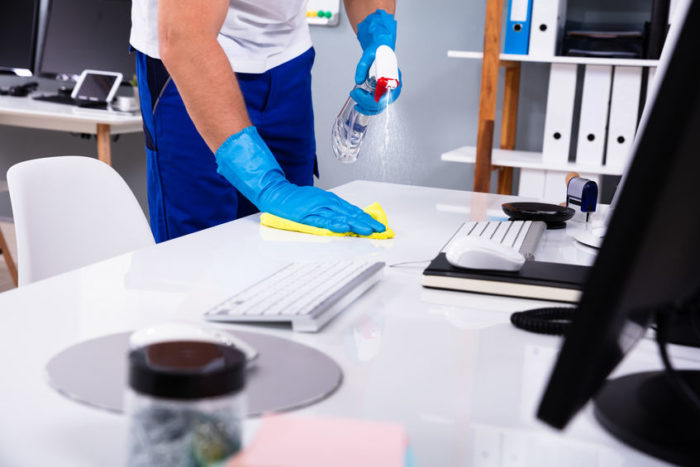 Janitor cleaning white desk in office Janitor cleaning white desk in modern office